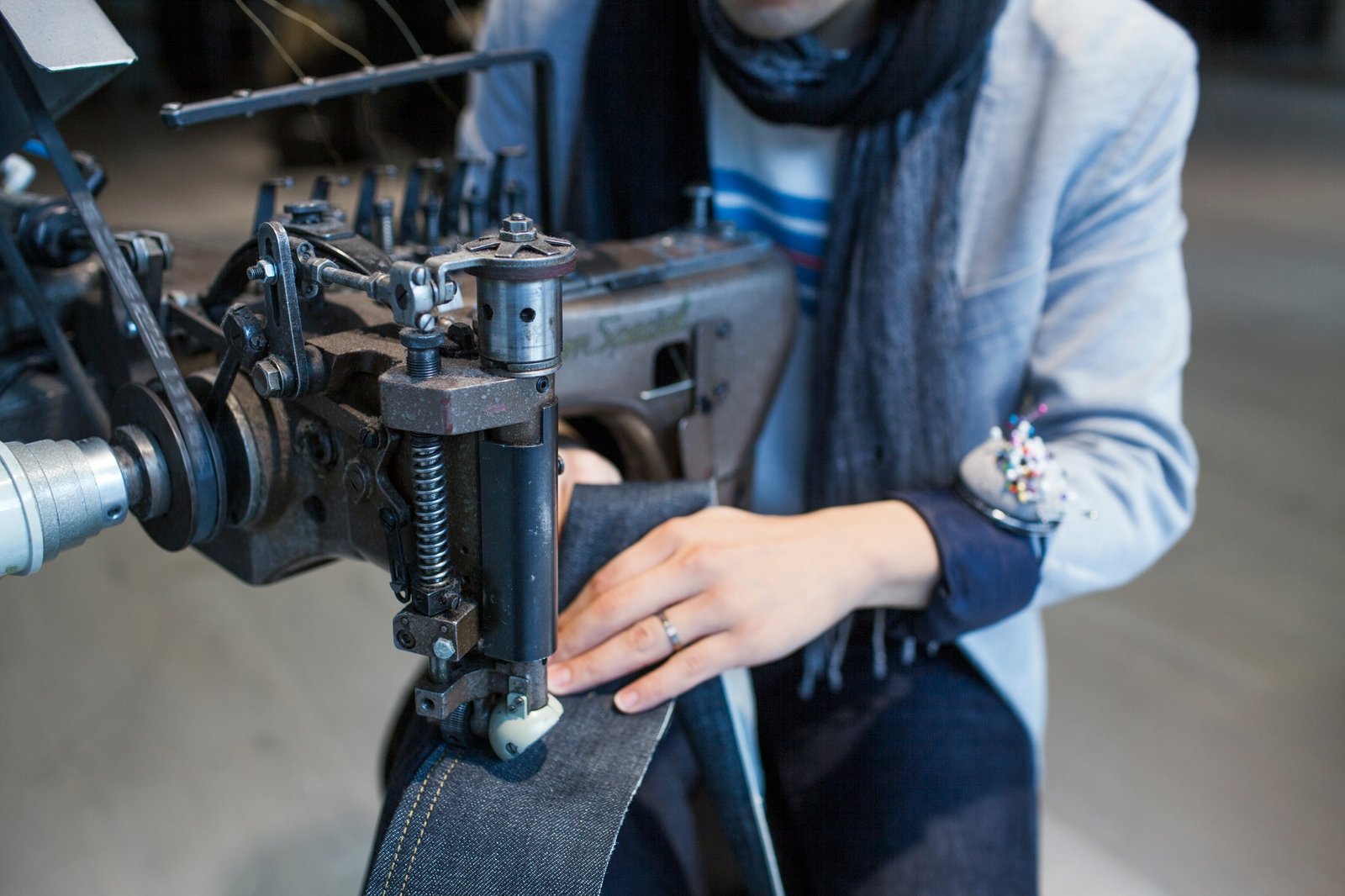 Midsection of male fashion designer using sewing machine in jeans factory