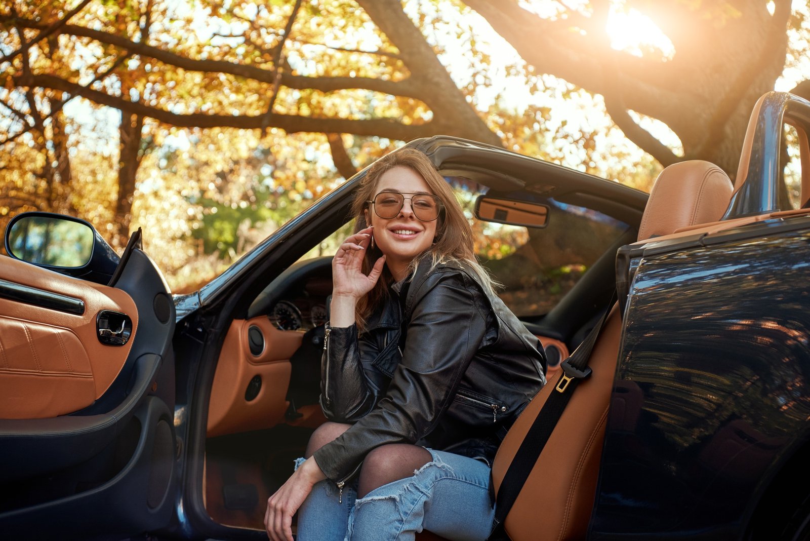 Sexy young woman in jeans smiling in a cabriolet